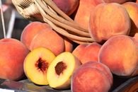 Close-up of ripe peaches in a rustic basket, showcasing vibrant colors and juicy texture.